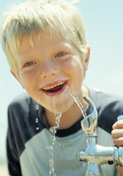 Boy drinking from a water fountain.