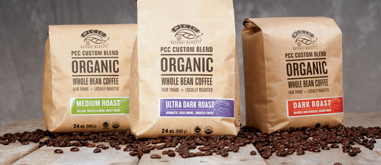 Three bags of PCC-branded coffee beans atop loose coffee beans.