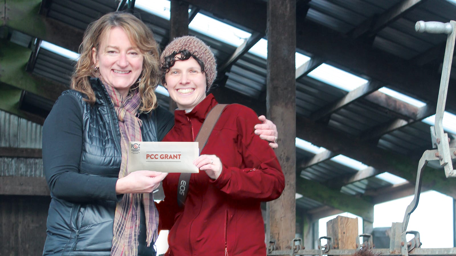 Green Lake Village PCC store director Celeste Coxen gives Jennifer McKeown a PCC Grant.