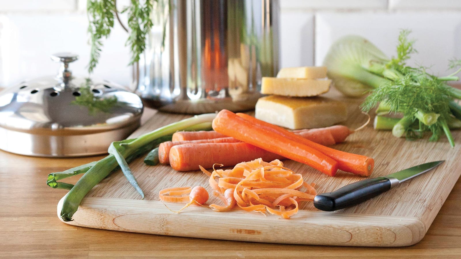 Carrot peels, fennel, cheese, green onions on a cutting board in front of a compost bin. Photo credit: Shannon Douglas