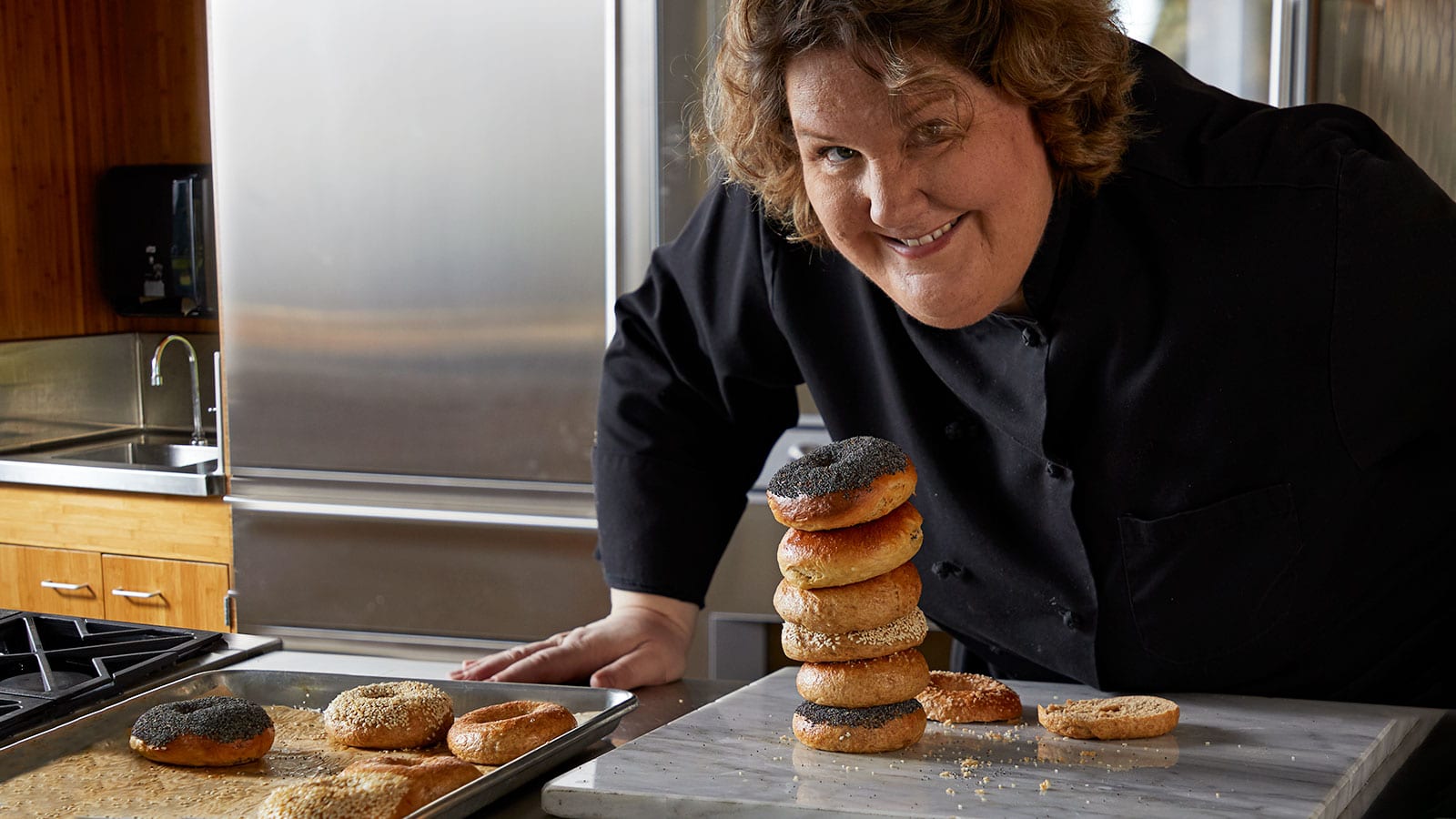 PCC Cooks instructor, Laurie Pfalzer, proudly poses with fresh baked bagels from her class, Homemade Bagels and Pretzels.