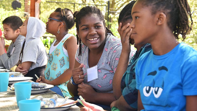 Young girls eating around a picnic table at Green Plate Special event. 