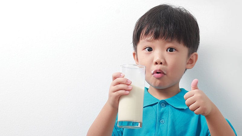 Adorable little boy holding a glass of milk.