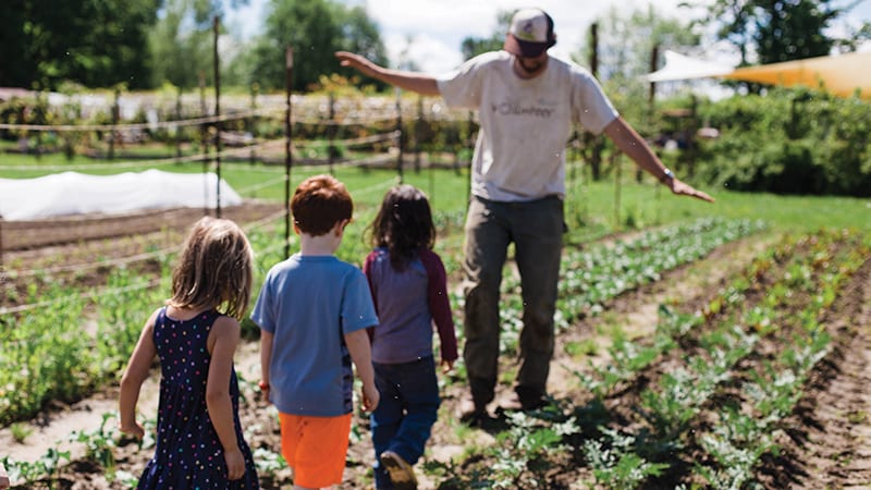 Teacher guiding young children through a small crop field