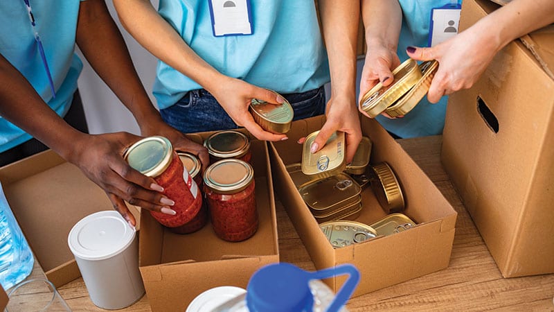 Hands compiling donation boxes at a food bank.