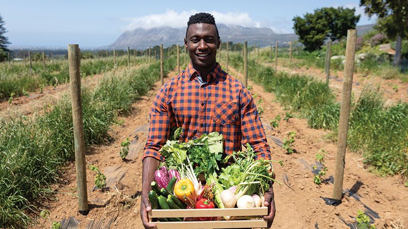 black farmer holding vegetables
