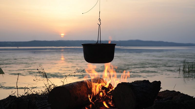 Campfire cooking in front of ocean