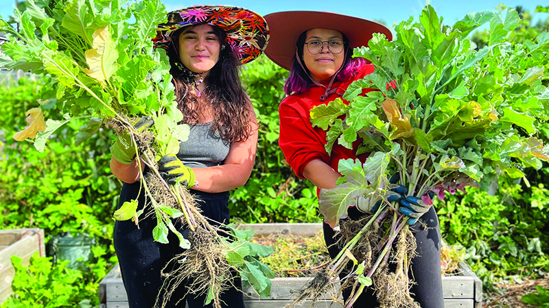 two women holding veggies