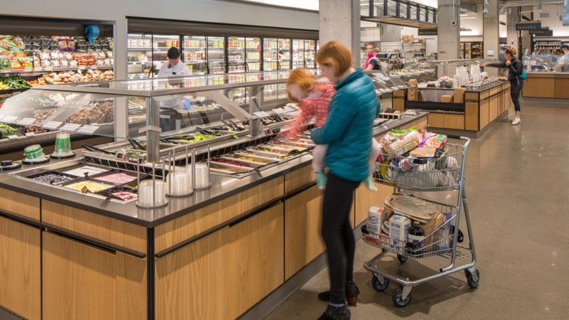 A parent and child shopping in the fresh deli section of PCC.