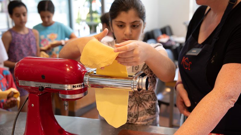 Fresh pasta being fed through a Kitchen Aid pasta attachment