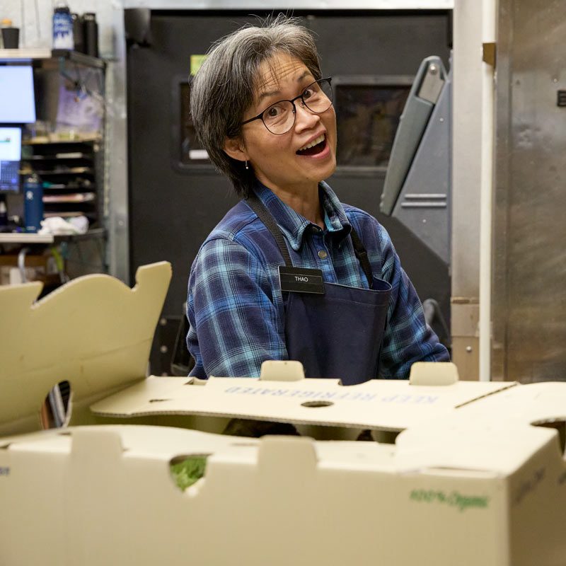 Thao in the back room cleaning and sorting produce