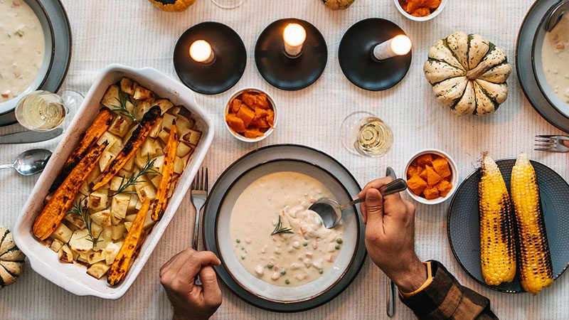 A table set with a vegetable soup and roasted vegetables.